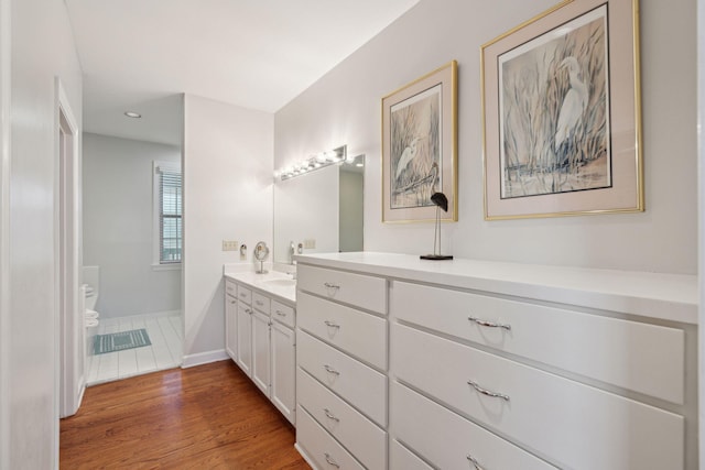 bathroom with hardwood / wood-style flooring, vanity, and toilet