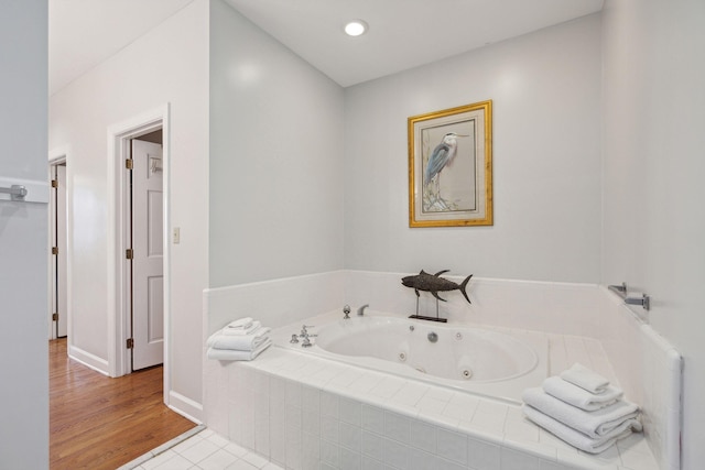 bathroom with tiled tub and hardwood / wood-style flooring