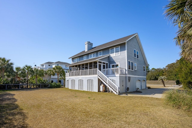 back of property featuring a garage, a sunroom, and a yard