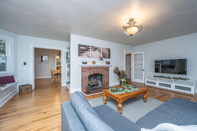 living room with wood-type flooring and a brick fireplace