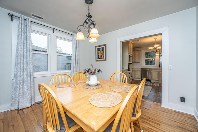 dining room featuring a healthy amount of sunlight, an inviting chandelier, and light hardwood / wood-style floors