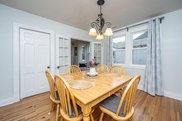 dining space with an inviting chandelier and light hardwood / wood-style floors