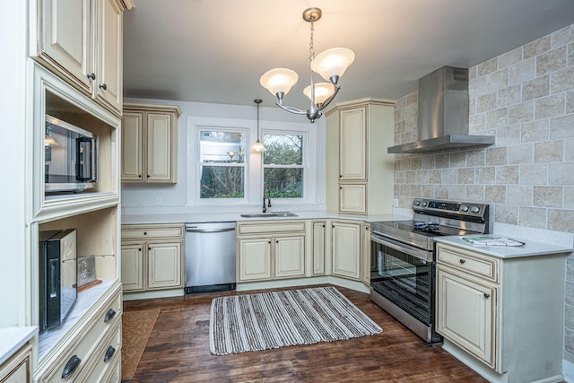 kitchen with appliances with stainless steel finishes, sink, cream cabinets, and wall chimney range hood