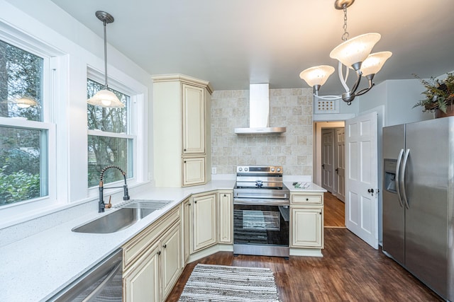 kitchen featuring decorative light fixtures, sink, stainless steel appliances, cream cabinets, and wall chimney exhaust hood