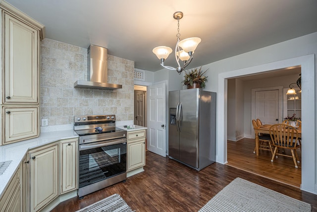 kitchen featuring dark hardwood / wood-style floors, wall chimney exhaust hood, stainless steel appliances, an inviting chandelier, and cream cabinetry