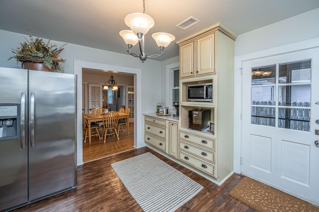 kitchen with cream cabinetry, appliances with stainless steel finishes, an inviting chandelier, and decorative light fixtures