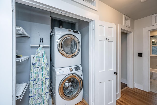 washroom featuring wood-type flooring and stacked washing maching and dryer