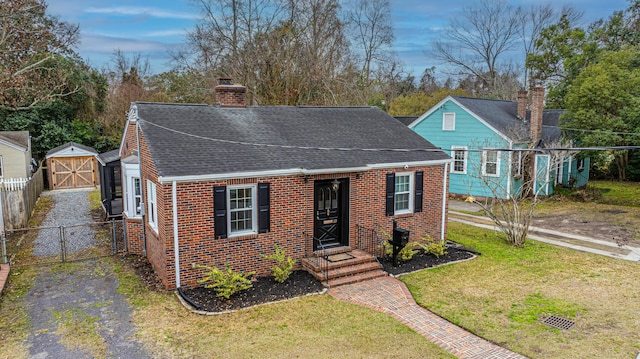 view of front of house with a storage shed and a front lawn