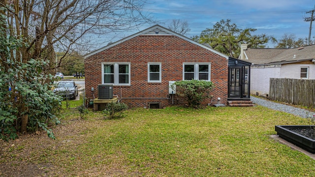 rear view of property featuring central AC and a lawn