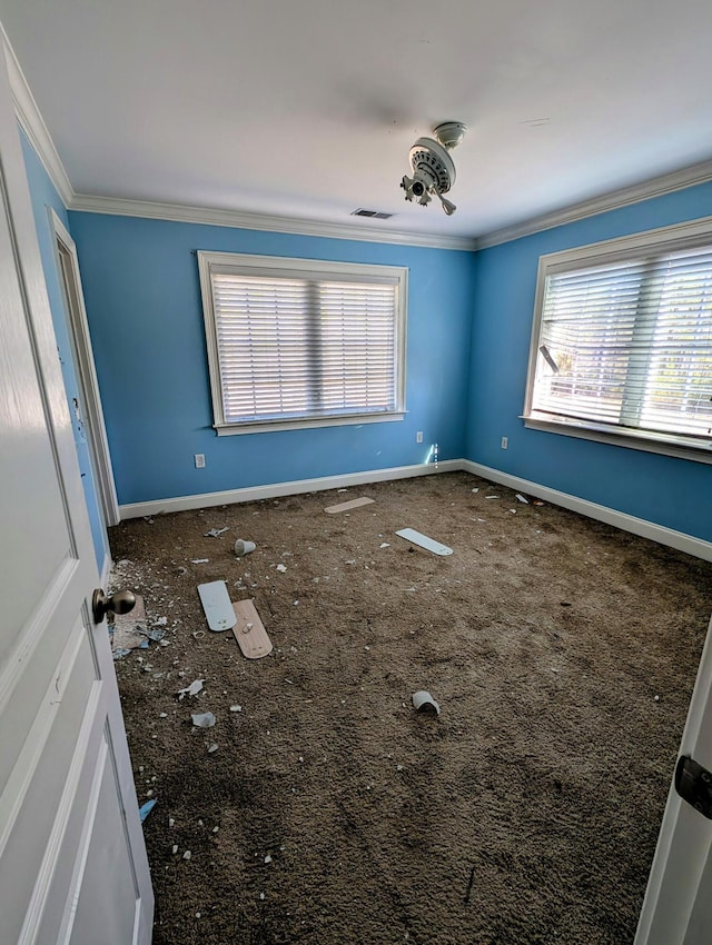spare room featuring crown molding, visible vents, and baseboards