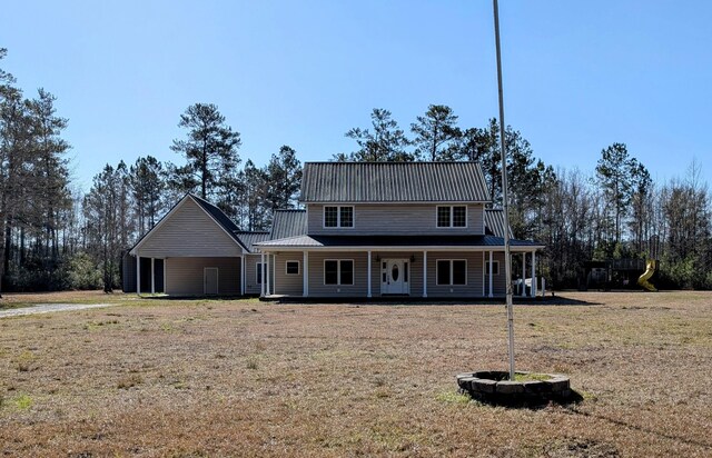 farmhouse featuring covered porch, metal roof, and a front yard