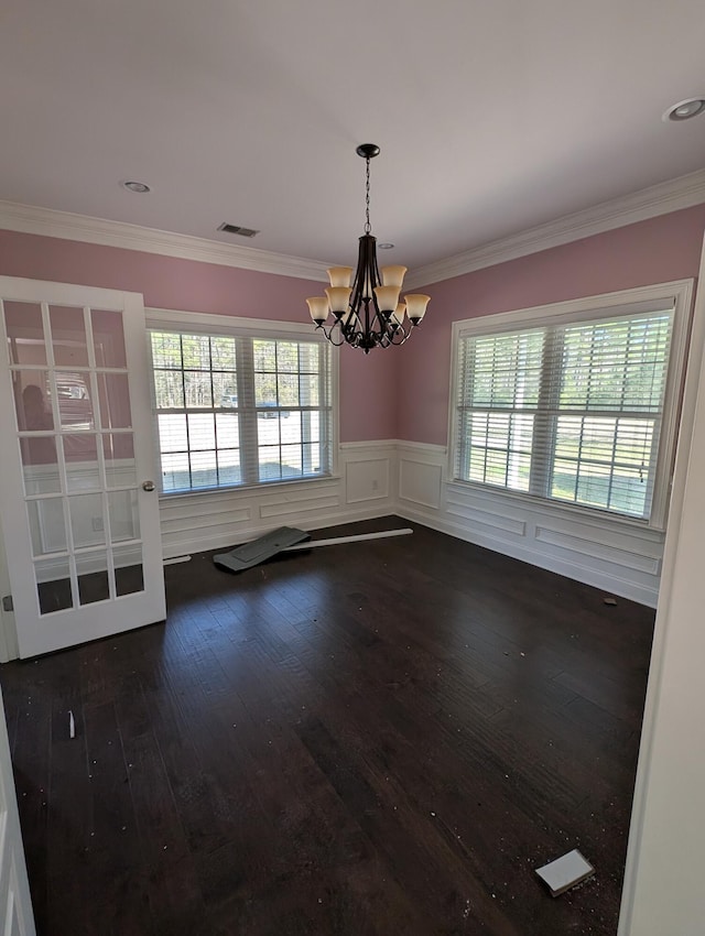 unfurnished room with a wainscoted wall, visible vents, dark wood finished floors, ornamental molding, and a notable chandelier