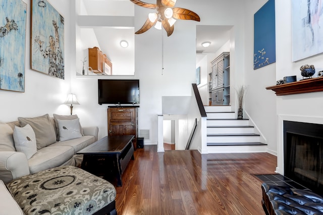 living room with a high ceiling, dark wood-type flooring, and ceiling fan