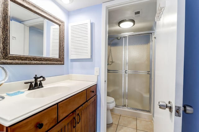 bathroom with vanity, toilet, tile floors, and a shower with door