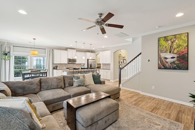 living room featuring crown molding, ceiling fan, and light hardwood / wood-style flooring