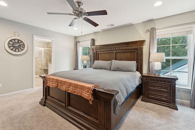 bedroom with ensuite bath, light colored carpet, and ceiling fan