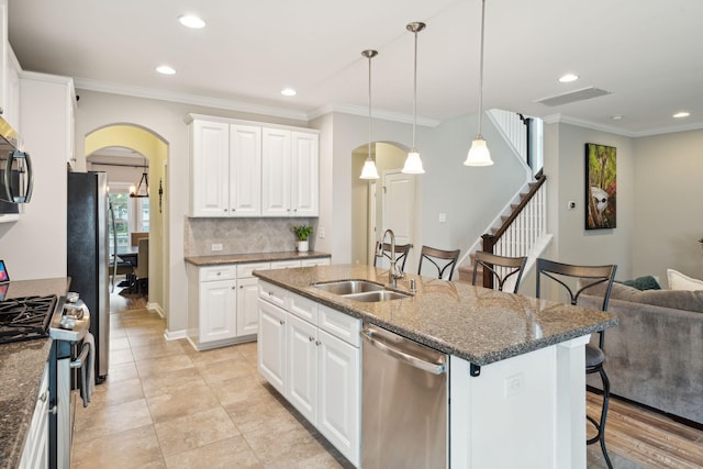 kitchen with stainless steel appliances, white cabinetry, and a kitchen island with sink