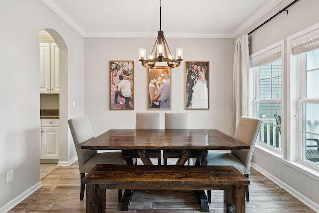 dining space featuring ornamental molding, an inviting chandelier, and light hardwood / wood-style flooring