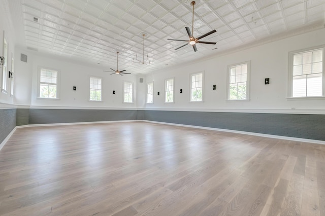 unfurnished room with an ornate ceiling, a healthy amount of sunlight, wood finished floors, and a ceiling fan