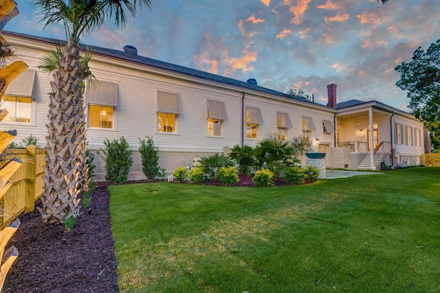 back of property at dusk featuring a yard