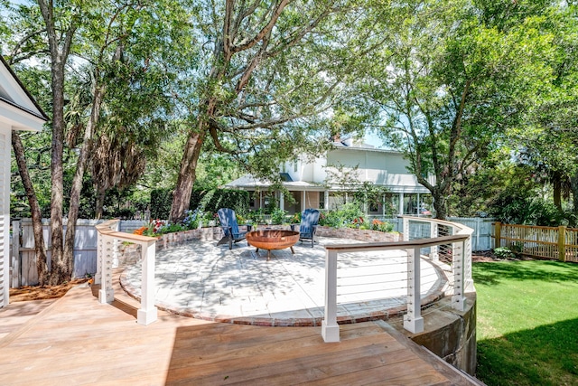 wooden terrace featuring a yard, fence, and an outdoor fire pit