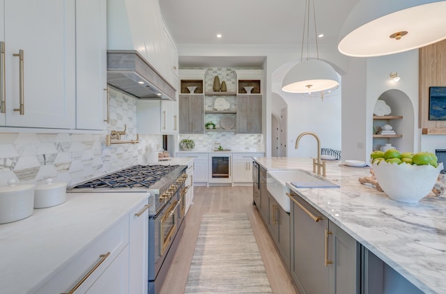 kitchen with a sink, wine cooler, custom range hood, high end range, and open shelves