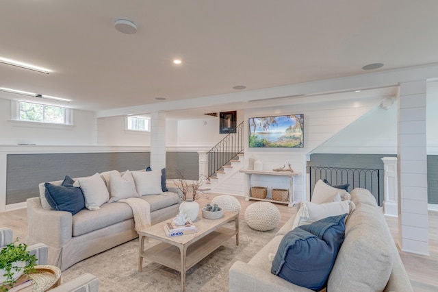 living room featuring recessed lighting, light wood-type flooring, stairs, and ornate columns