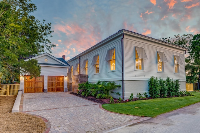 view of front of home featuring decorative driveway, a front lawn, and fence