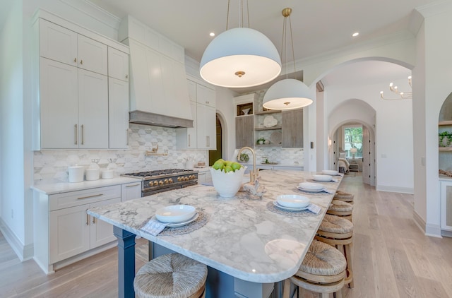 kitchen featuring premium range hood, open shelves, arched walkways, a breakfast bar area, and range with two ovens