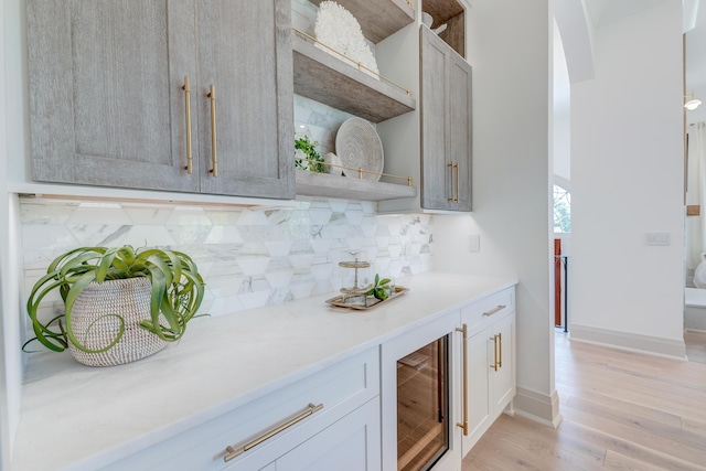 kitchen with light wood-type flooring, open shelves, backsplash, wine cooler, and light countertops