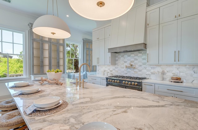 kitchen with backsplash, light stone countertops, ornamental molding, high end range, and a sink