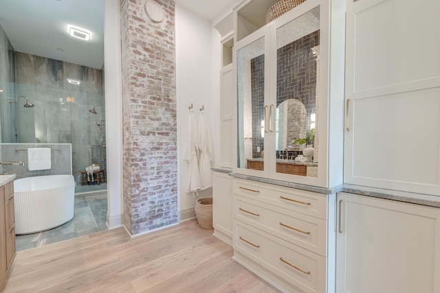 full bathroom with visible vents, wood finished floors, a shower stall, a soaking tub, and vanity