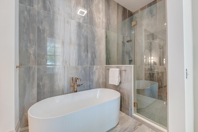 bathroom with a soaking tub, tile walls, and a stall shower