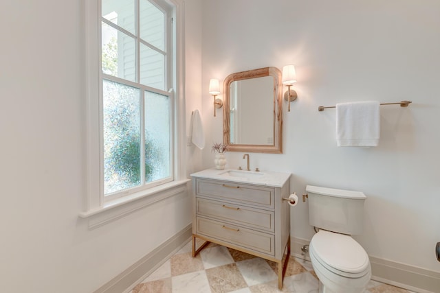 half bathroom featuring toilet, vanity, and baseboards