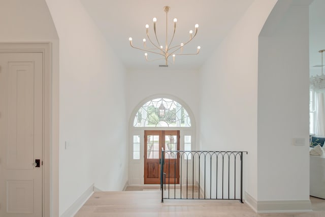 entryway featuring a notable chandelier, baseboards, arched walkways, and a towering ceiling