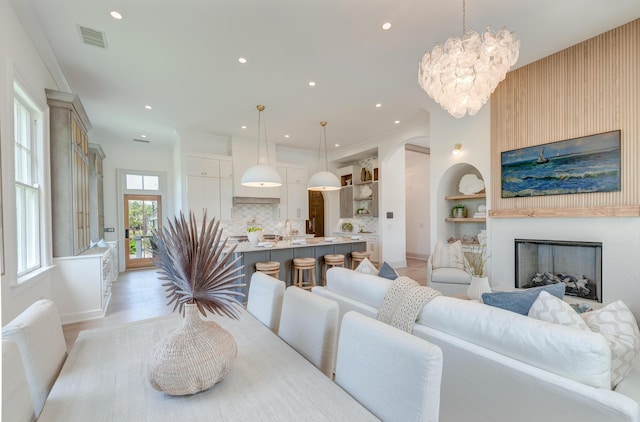 dining space with light wood finished floors, visible vents, recessed lighting, a fireplace, and an inviting chandelier