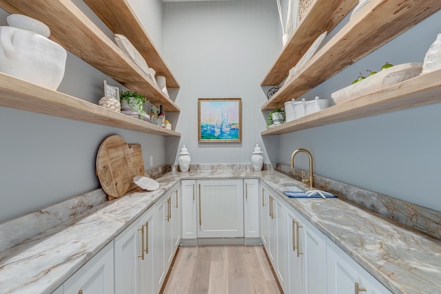 interior space with white cabinetry, open shelves, light wood-style floors, and light stone countertops