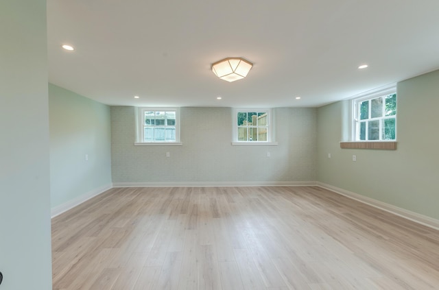 below grade area with recessed lighting, brick wall, light wood-type flooring, and baseboards