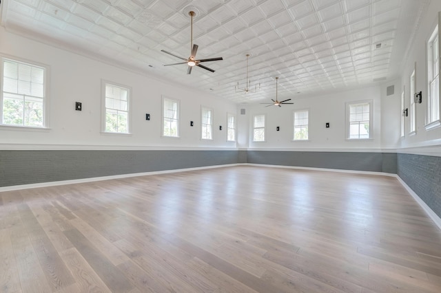 spare room with wood finished floors, a healthy amount of sunlight, an ornate ceiling, and ceiling fan