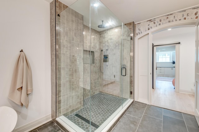 full bath featuring tile patterned flooring, a stall shower, and baseboards