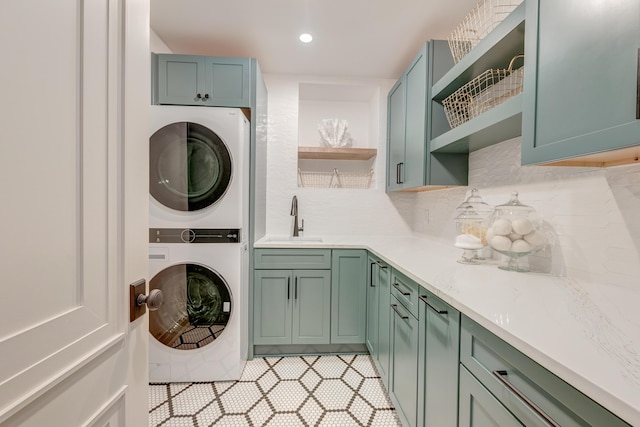 laundry room with a sink, stacked washer / drying machine, cabinet space, and recessed lighting