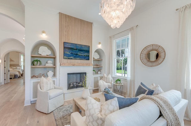 living room with built in features, light wood-style floors, and arched walkways