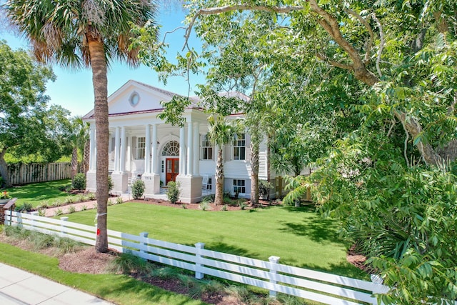 greek revival house with a front yard, fence private yard, and covered porch