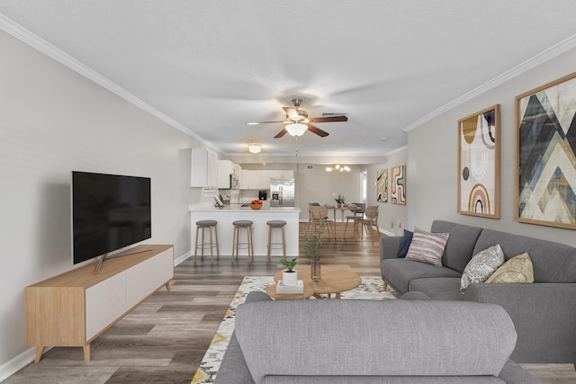 living room with ceiling fan, ornamental molding, and wood-type flooring