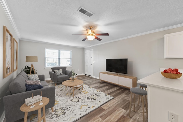 living room with ornamental molding, ceiling fan, a textured ceiling, and dark hardwood / wood-style floors