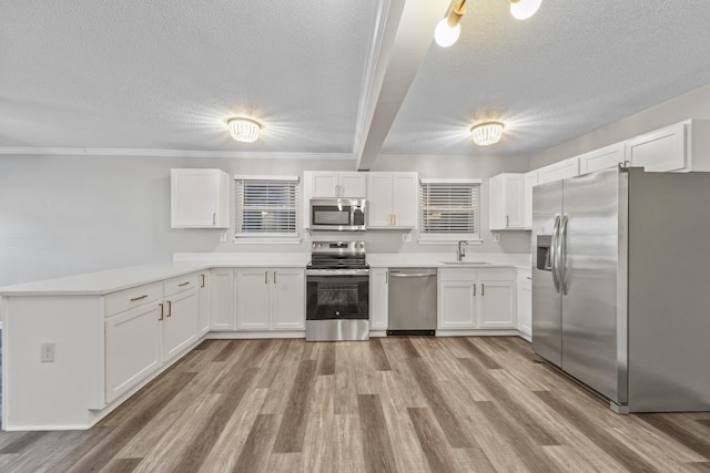 kitchen featuring a textured ceiling, stainless steel appliances, crown molding, white cabinetry, and sink