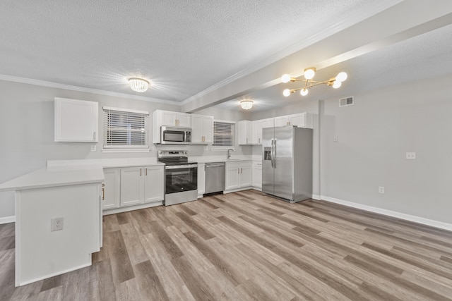 kitchen with stainless steel appliances, an inviting chandelier, crown molding, white cabinetry, and sink