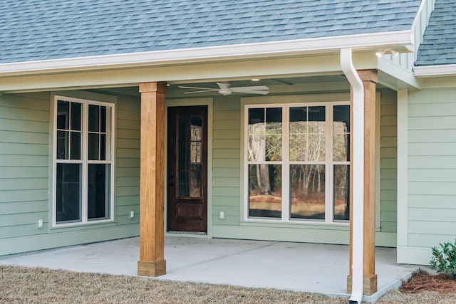 view of exterior entry with ceiling fan, a patio, and roof with shingles