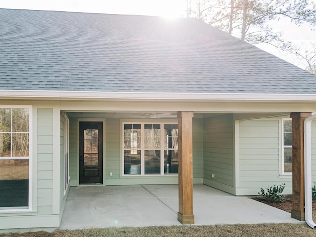 property entrance featuring a shingled roof and a patio