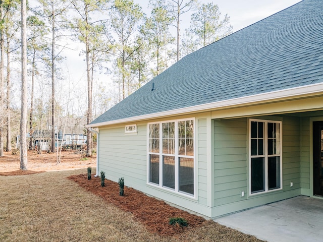 view of property exterior featuring a shingled roof and a patio